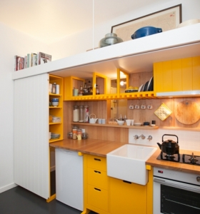 Mini cocina genial con armarios amarillos en un estudio de 23 metros cuadrados