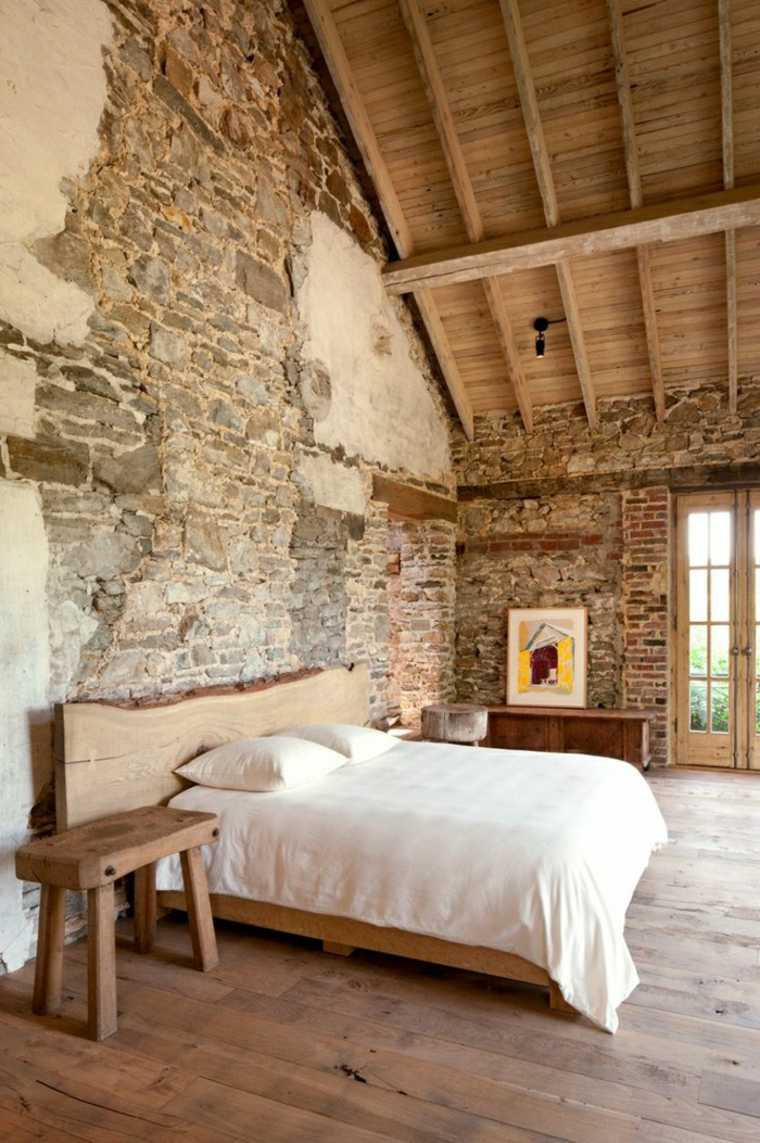 dormitorio con pared de piedra