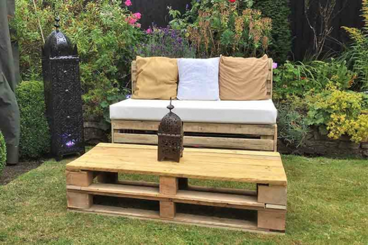 Zona chill out al aire libre amueblada con asientos de pallets reciclados